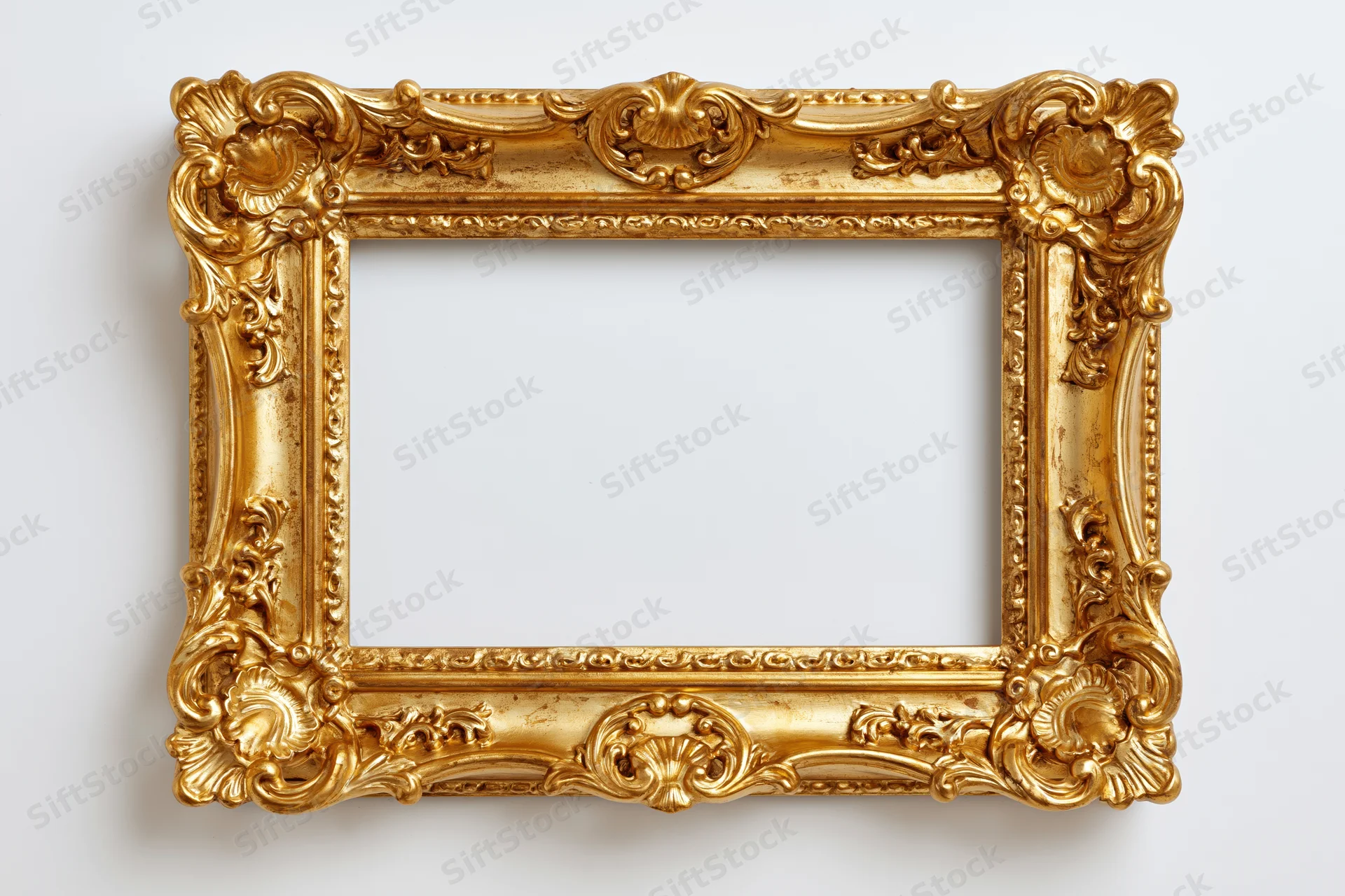 Ornate baroque gold picture frame with intricate carved scrollwork hanging on a white wall
