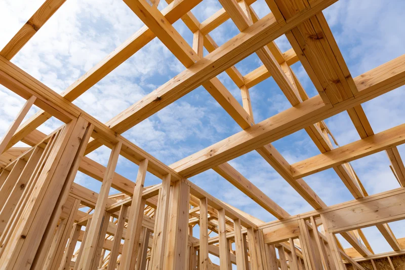 Wooden frame structure of a residential house under construction against a blue sky