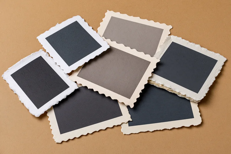 Vintage photo prints with deckle edges scattered on brown paper background