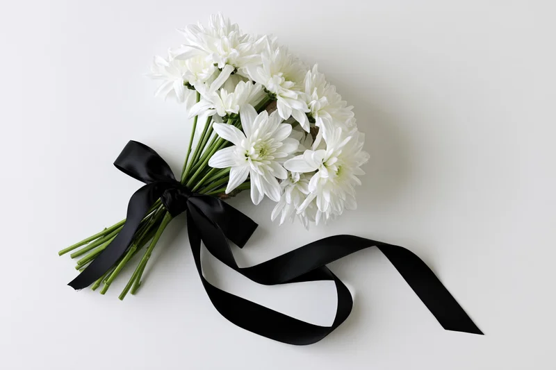 Small bouquet of white chrysanthemums tied with black satin ribbon on white background