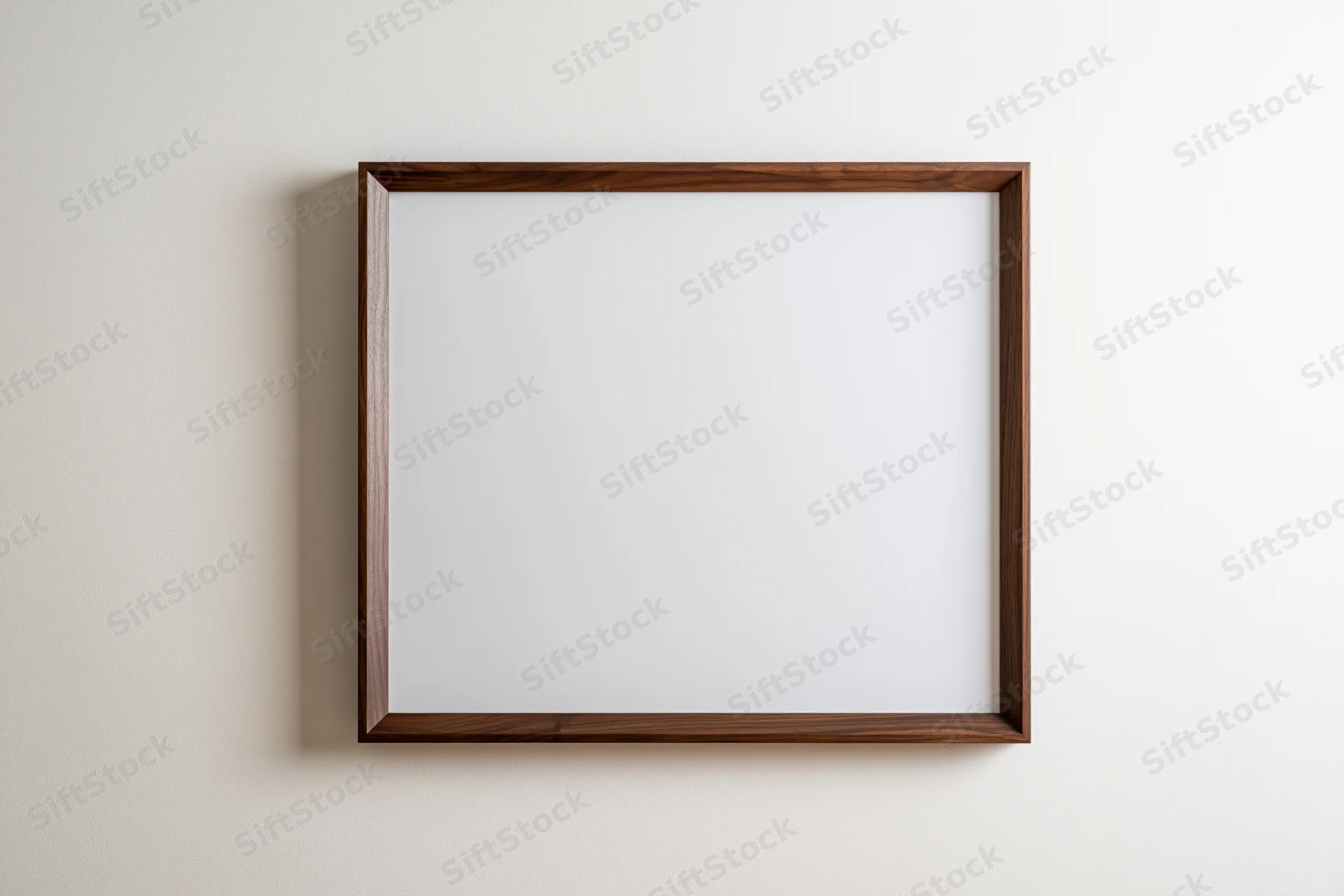 Dark walnut wood picture frame with blank white interior hanging on a light wall