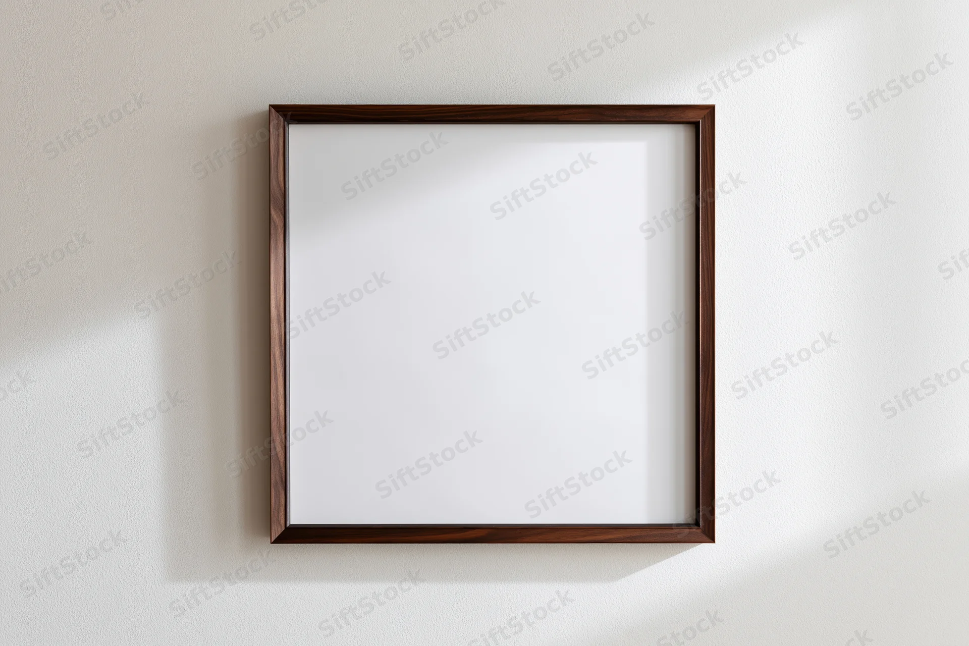 Dark walnut wood picture frame with blank white interior hanging on a white wall