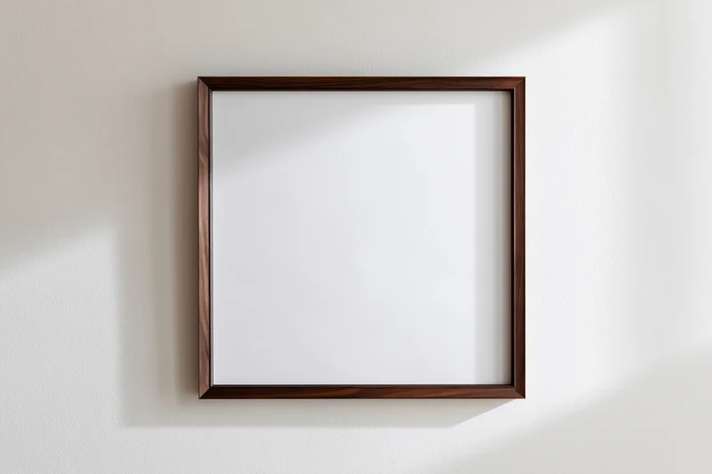 Dark walnut wood picture frame with blank white interior hanging on a white wall