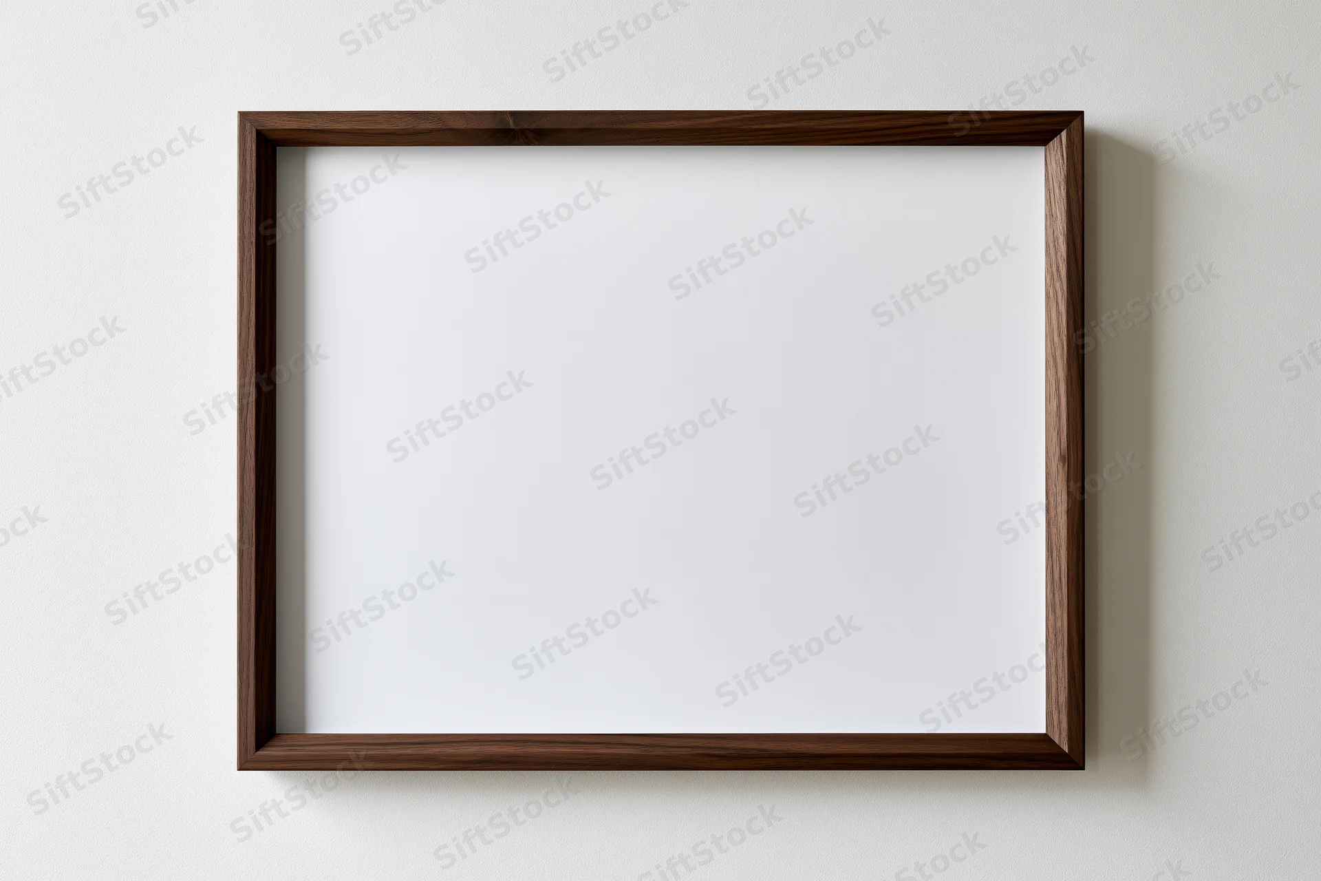 Dark walnut wood picture frame with blank white interior hanging on a white wall