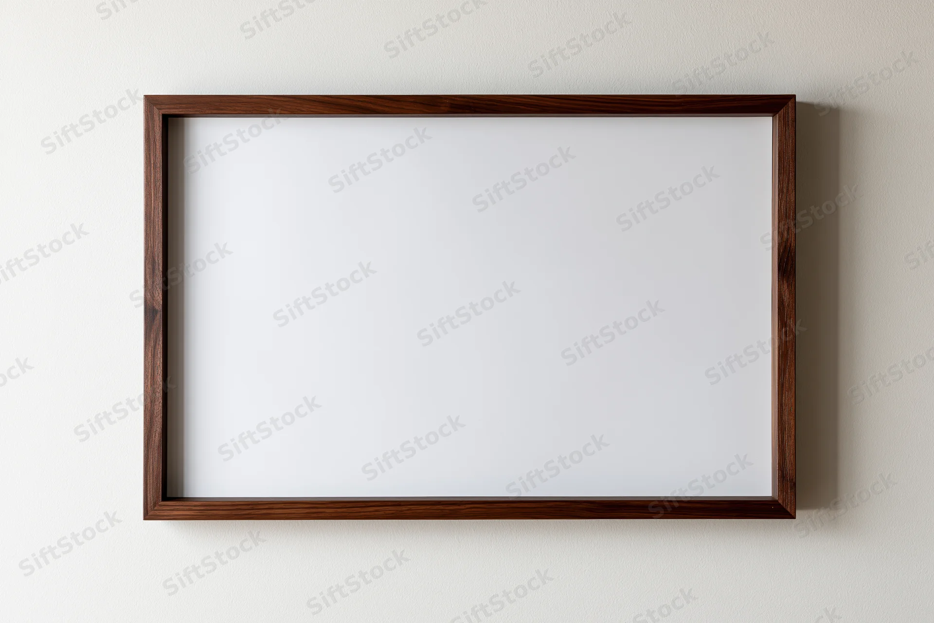 Dark walnut wood picture frame with blank white interior hanging on a white wall