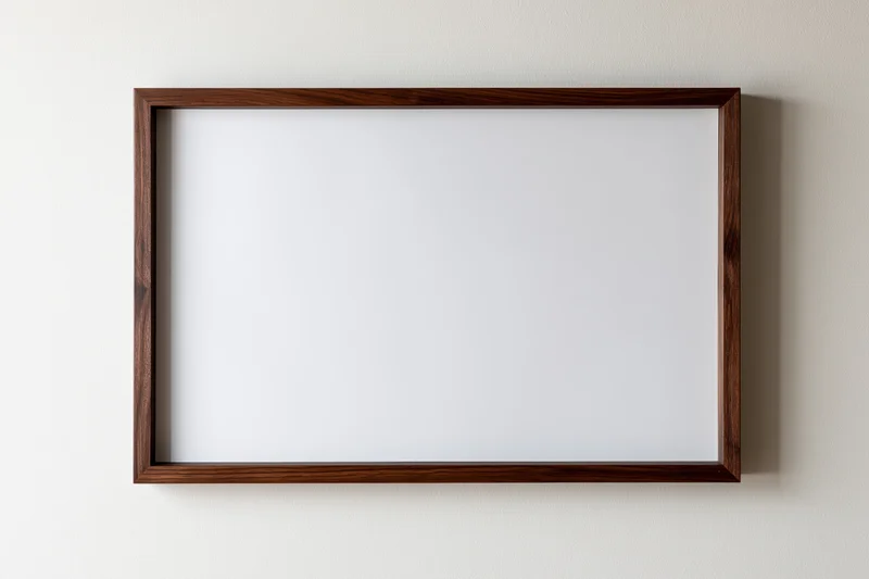 Dark walnut wood picture frame with blank white interior hanging on a white wall