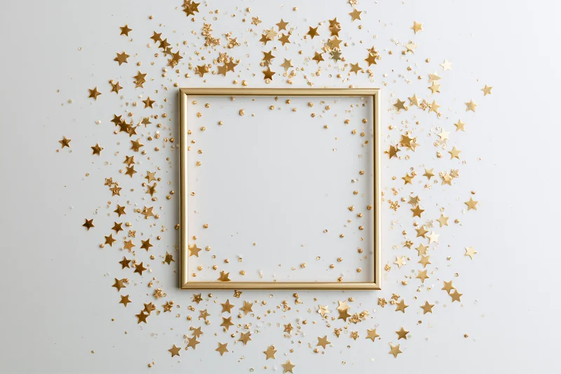 Gold frame with scattered star confetti on white surface