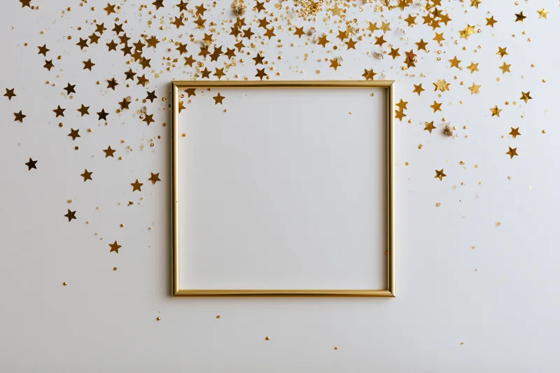 Gold picture frame with scattered star confetti on a white surface