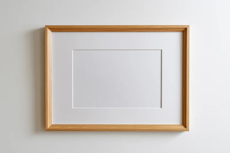 Light oak wooden picture frame with white mat hanging on a plain wall