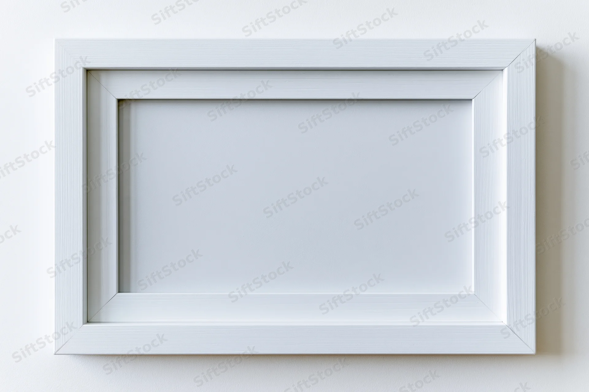 White rectangular picture frame with empty interior mounted on a plain wall