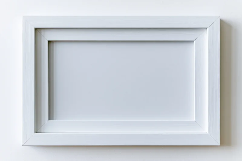 White rectangular picture frame with empty interior mounted on a plain wall