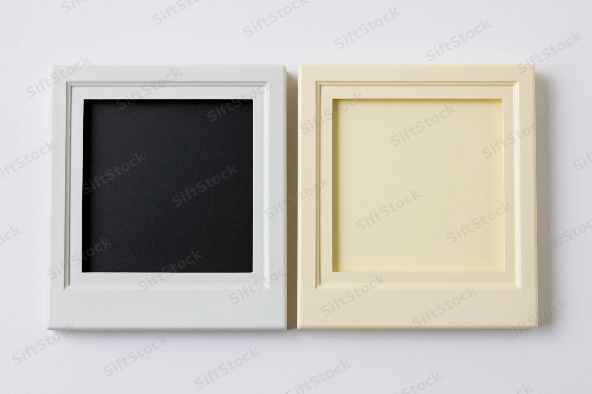 Two blank polaroid frames side by side on a white wall