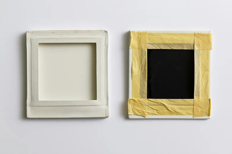 Two blank instant film photo prints side by side on white surface