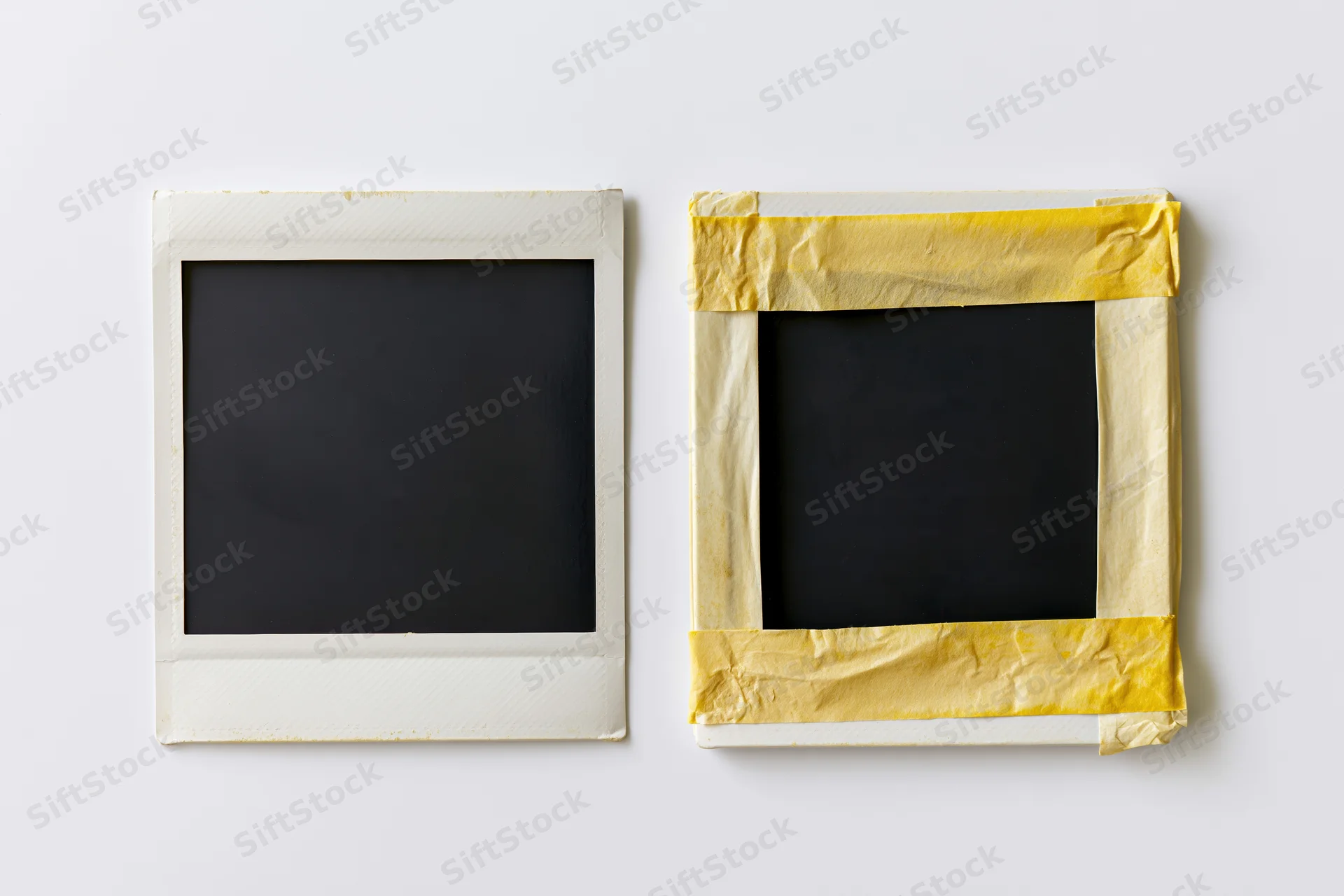 Two blank instant film photo prints side by side on a white surface, one with yellow tape border