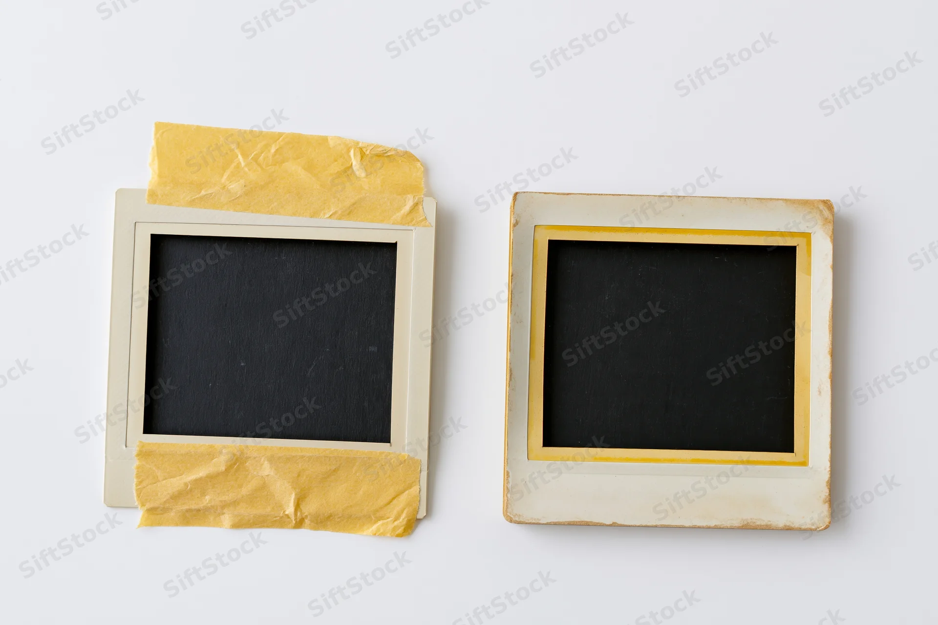 Two vintage polaroid photo frames lying flat on white surface with yellow tape and blank black centers