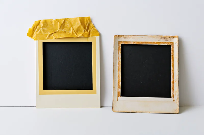 Two vintage polaroid photo frames with blank black surfaces on white background