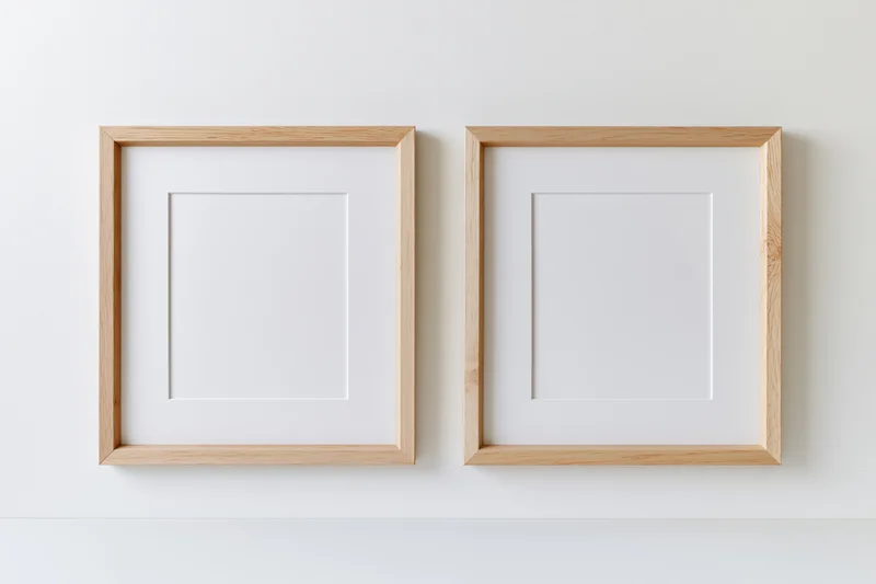 Two identical light wood picture frames with white mats hanging on a white wall