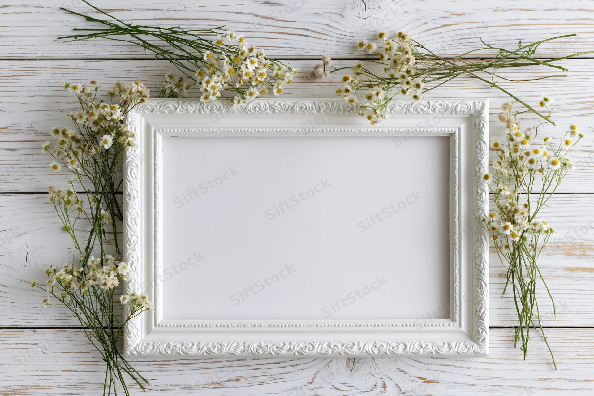 White ornate frame with daisies arranged on a whitewashed wooden surface