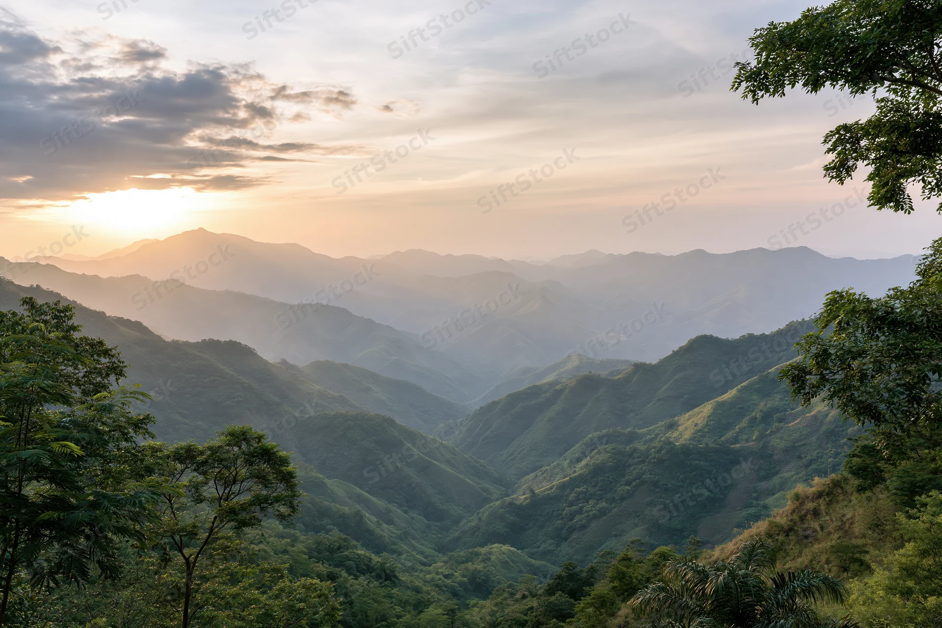 Layered green mountain ridges receding into misty horizon at sunset