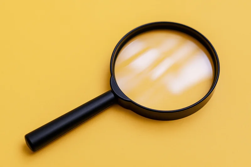 Black plastic magnifying glass lying flat on bright yellow background