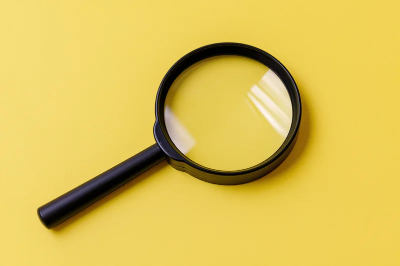 Black plastic magnifying glass lying flat on bright yellow background