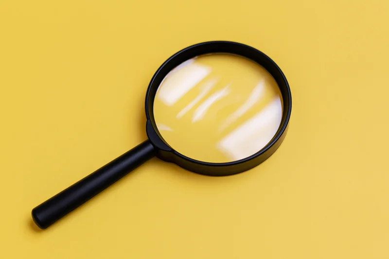 Black plastic magnifying glass lying flat on bright yellow surface