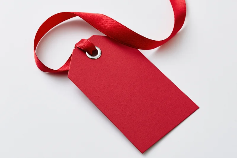 Red cardstock gift tag with ribbon on white background