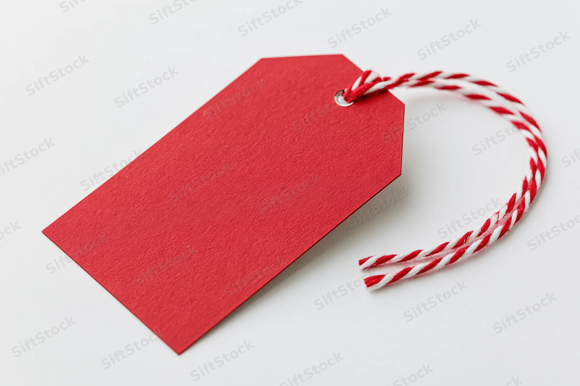 Blank red cardstock gift tag with red and white twisted string on white background