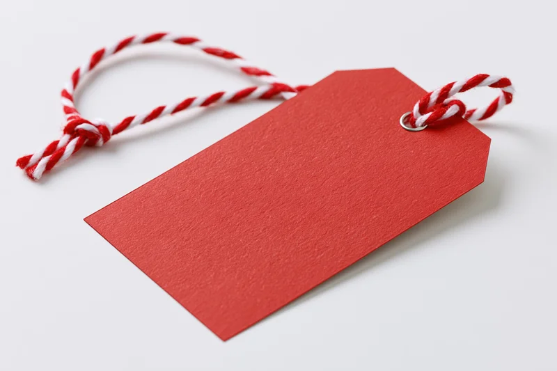 Blank red cardstock gift tag with red and white twisted string on white background