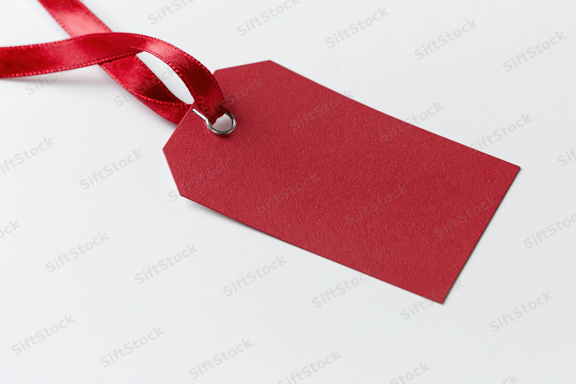 Red paper gift tag with satin ribbon on white background