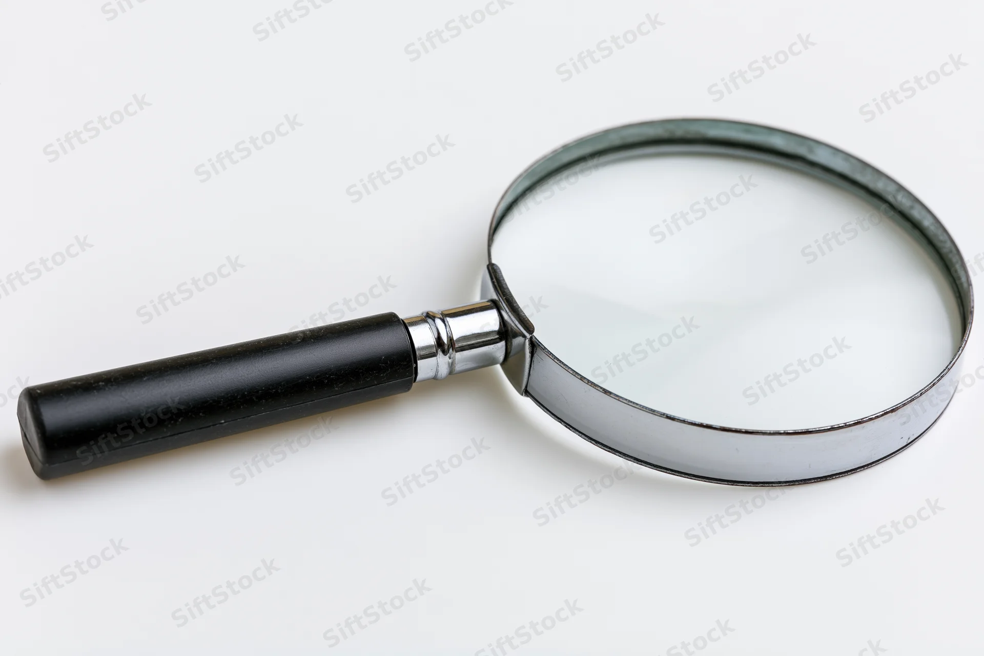 Classic black-handled magnifying glass lying flat on white surface