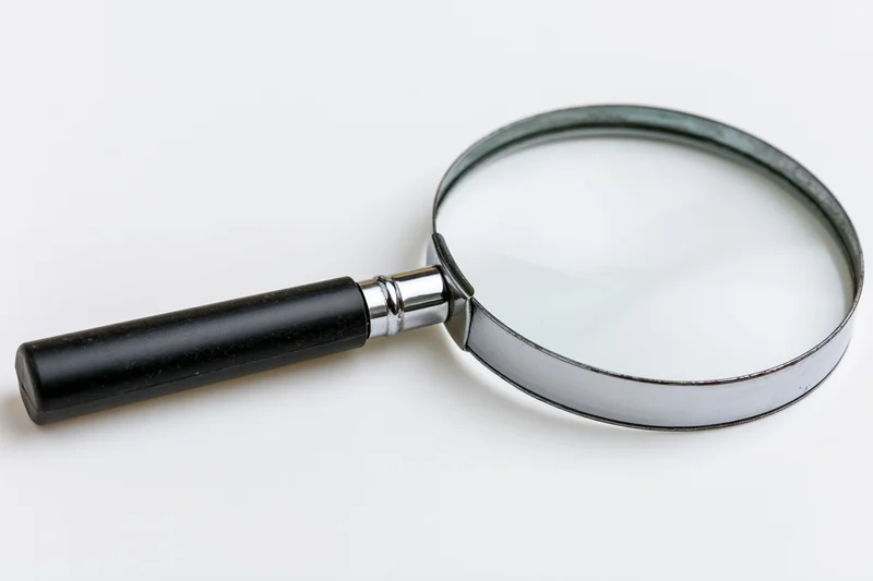 Classic black-handled magnifying glass lying flat on white surface