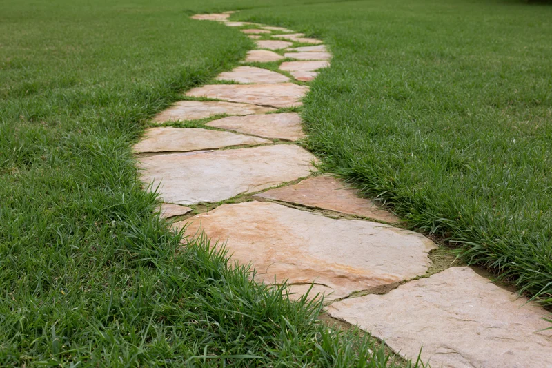 Flagstone garden path winding through closely trimmed lawn