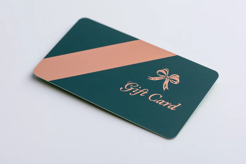 Dark teal and rose gold gift card lying flat on white surface