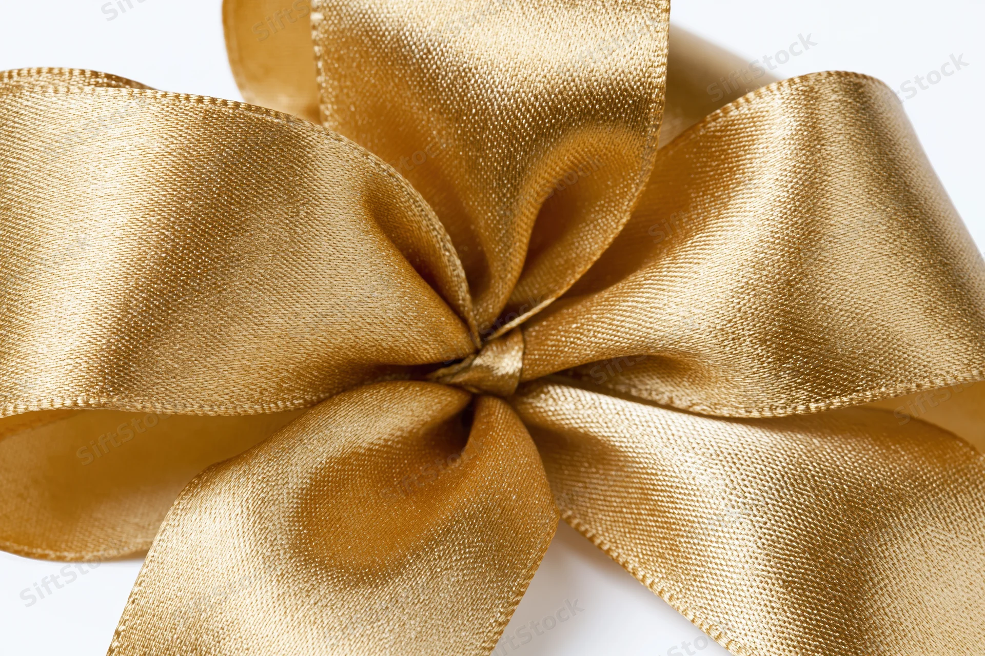 Gold satin ribbon tied into a decorative bow on white background