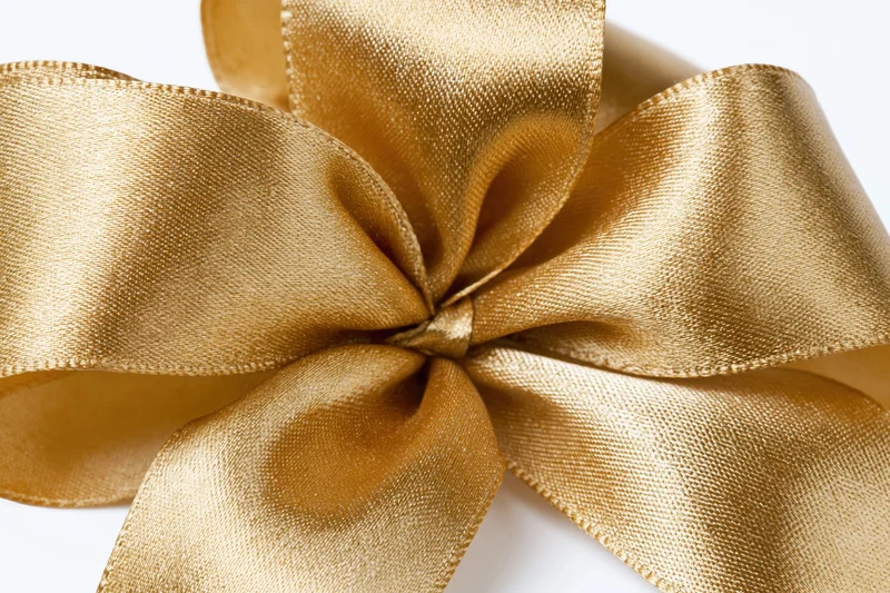 Gold satin ribbon tied into a decorative bow on white background