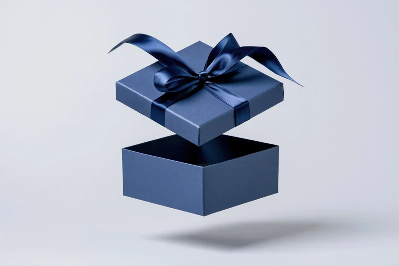Floating blue gift box with ribbon bow open against white background