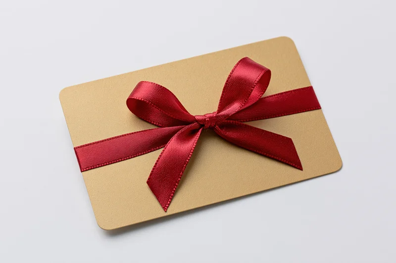 Gold gift card with red satin ribbon and bow on white background