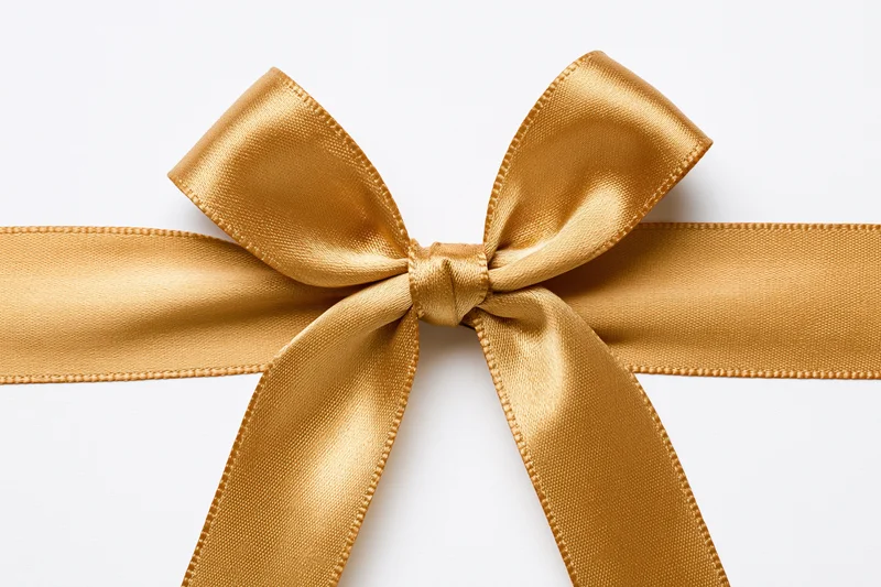 Golden satin ribbon tied into a bow centered on a white background