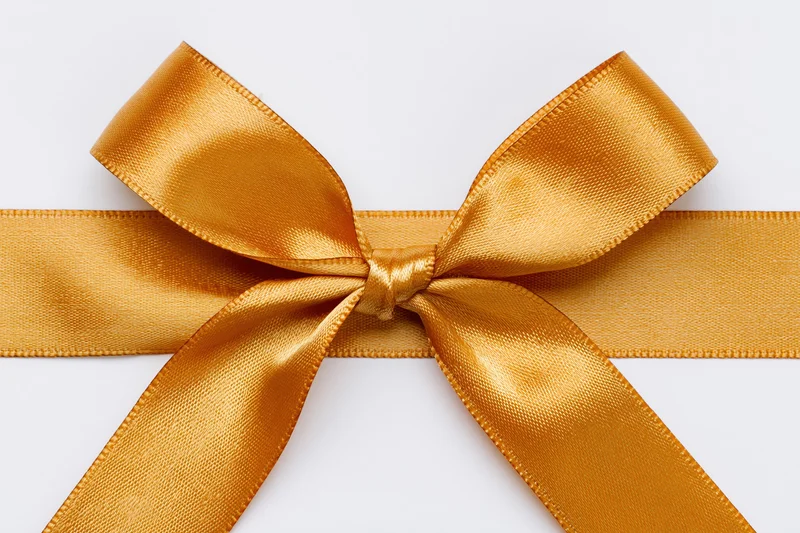 Golden satin ribbon tied into a bow centered on a white background