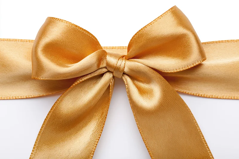 Golden satin ribbon tied into a bow centered on a white background