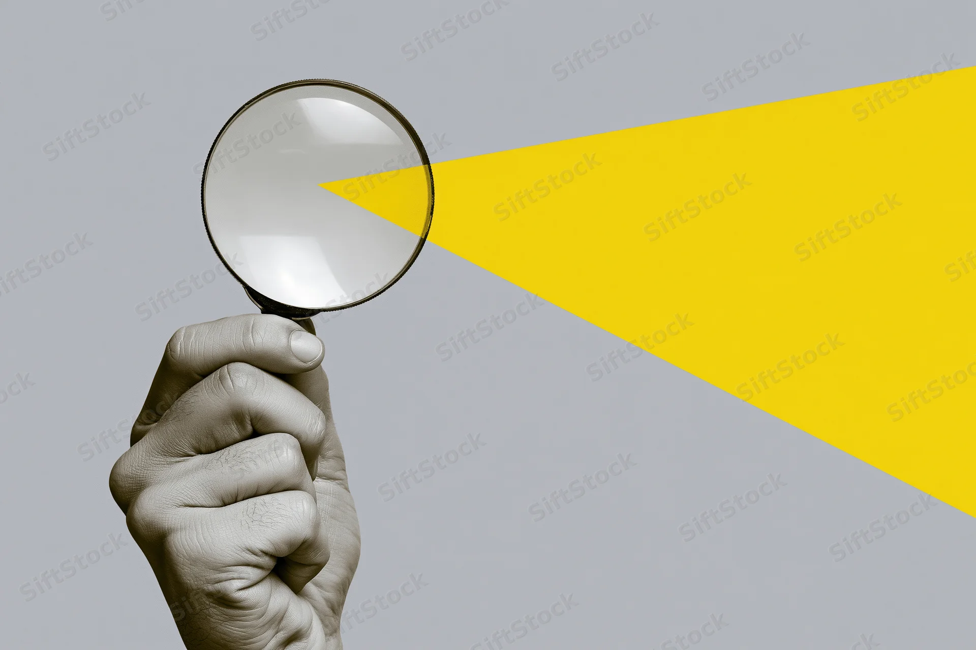 Hand holding magnifying glass against gray and yellow background
