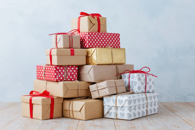 Stack of wrapped gift boxes arranged in pyramid shape on wooden table