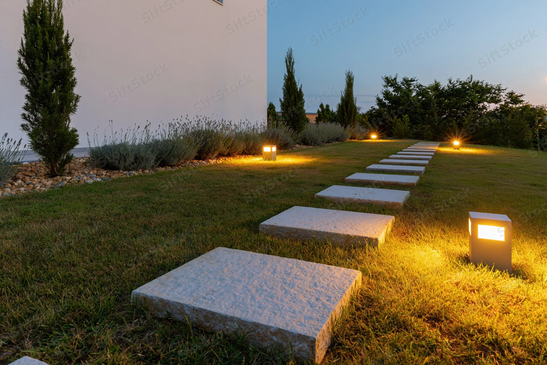 Modern garden pathway with stone stepping stones and ground lights at dusk