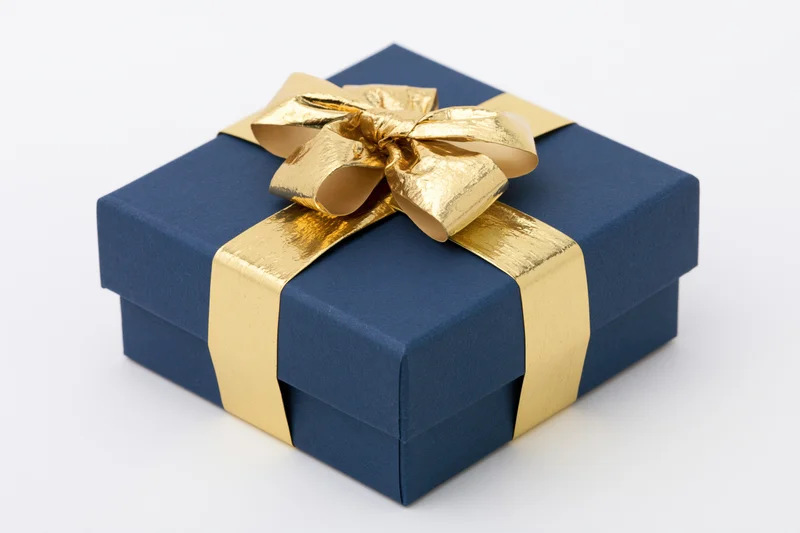 Navy blue gift box wrapped with gold metallic ribbon and bow on white background