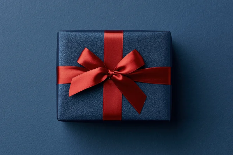 Dark blue gift box with red satin ribbon bow on textured surface