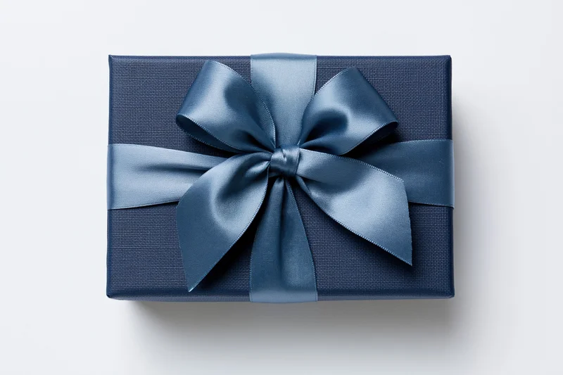 Navy gift box wrapped with satin ribbon bow on white background