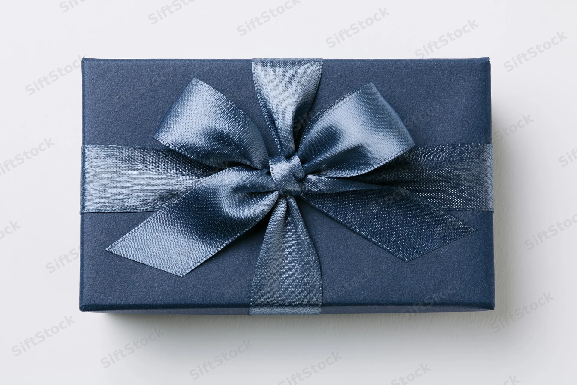 Navy gift box wrapped with satin ribbon bow on white background