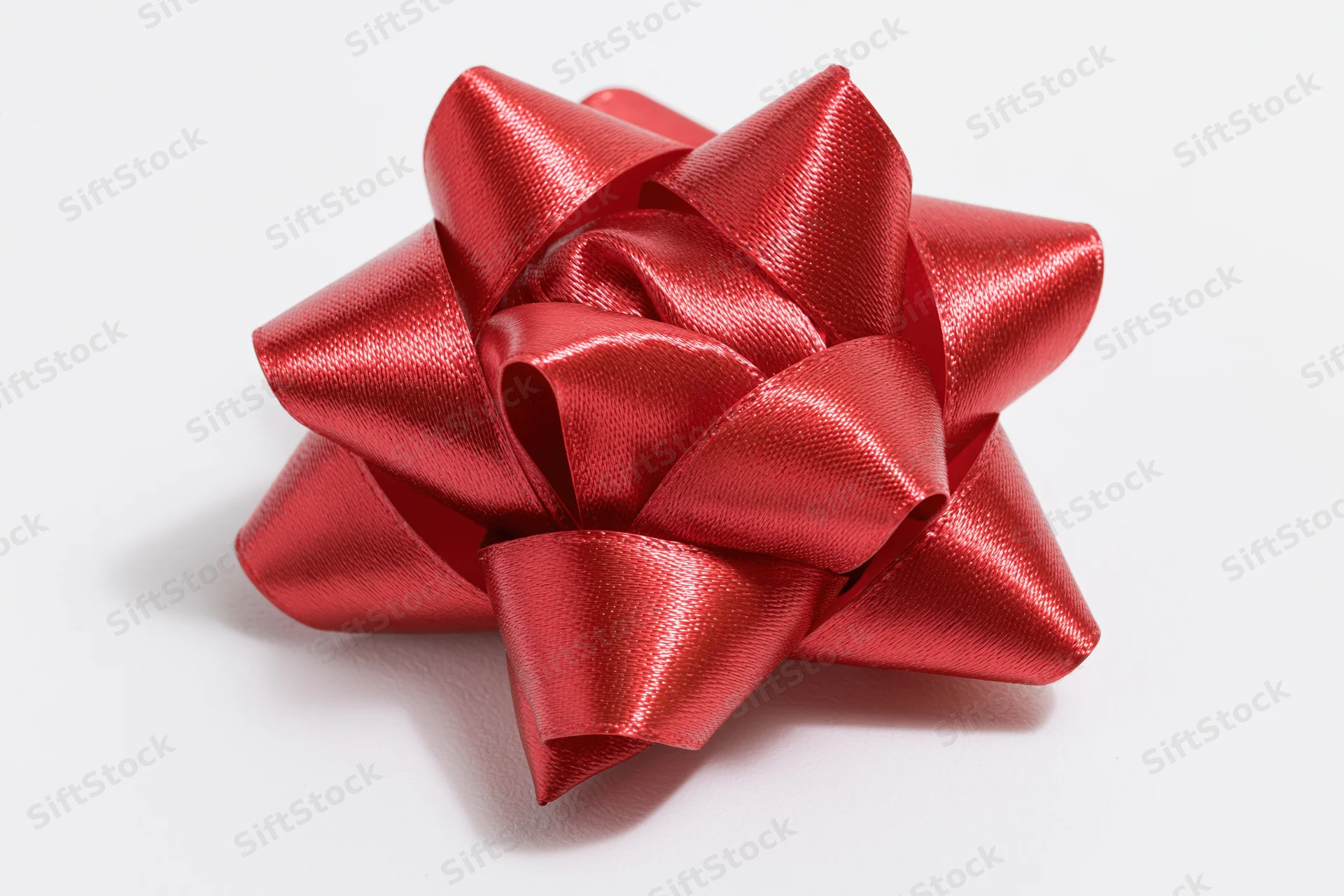 Red satin gift bow on white background with copyspace