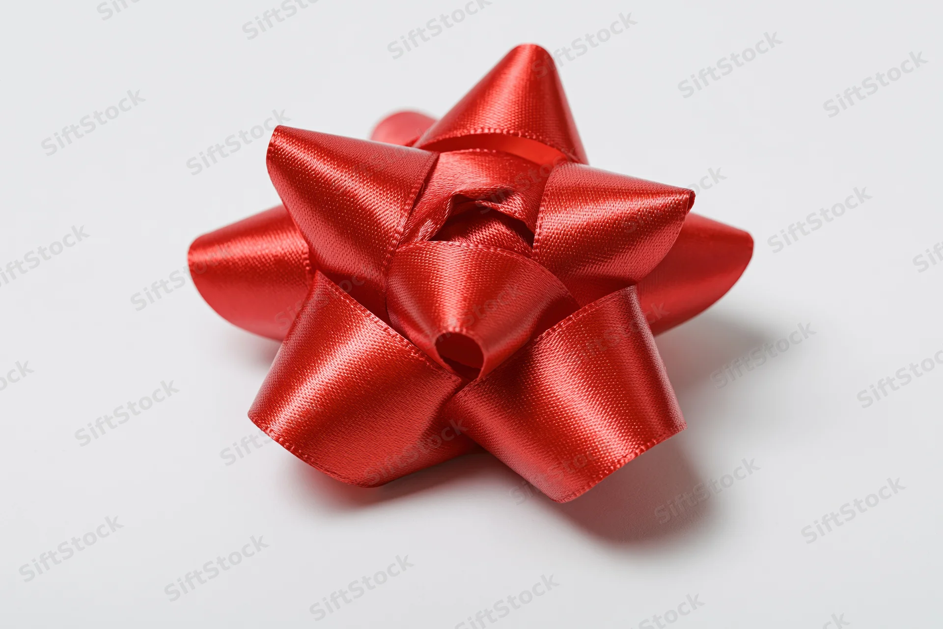 Red satin gift bow on white background with copyspace